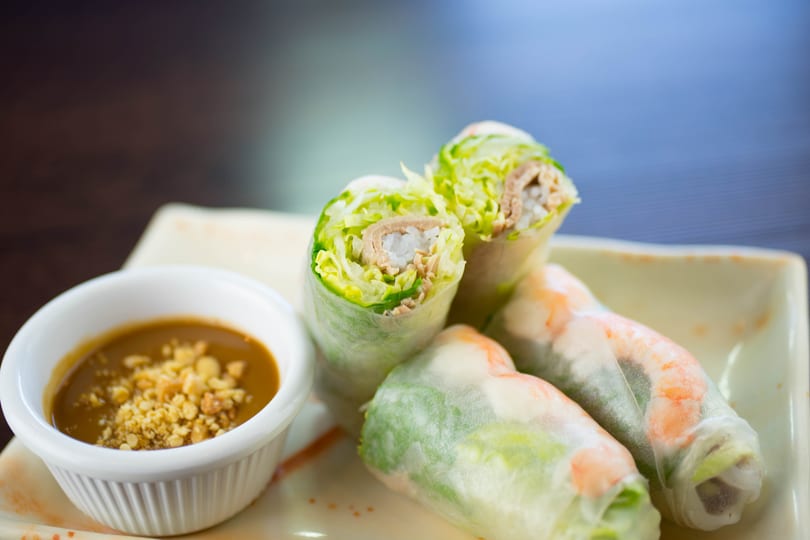 Fresh spring rolls with shrimp, pork, and lettuce, served with a side of peanut sauce.