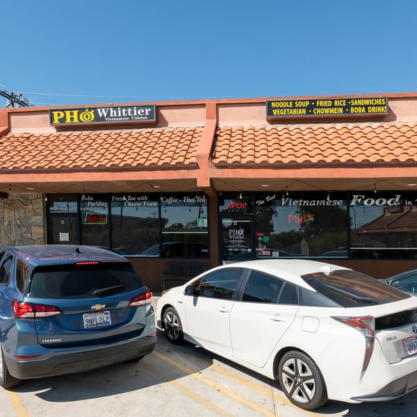 Pho Whittier Vietnamese Cuisine restaurant exterior with cars parked in front on a sunny day.