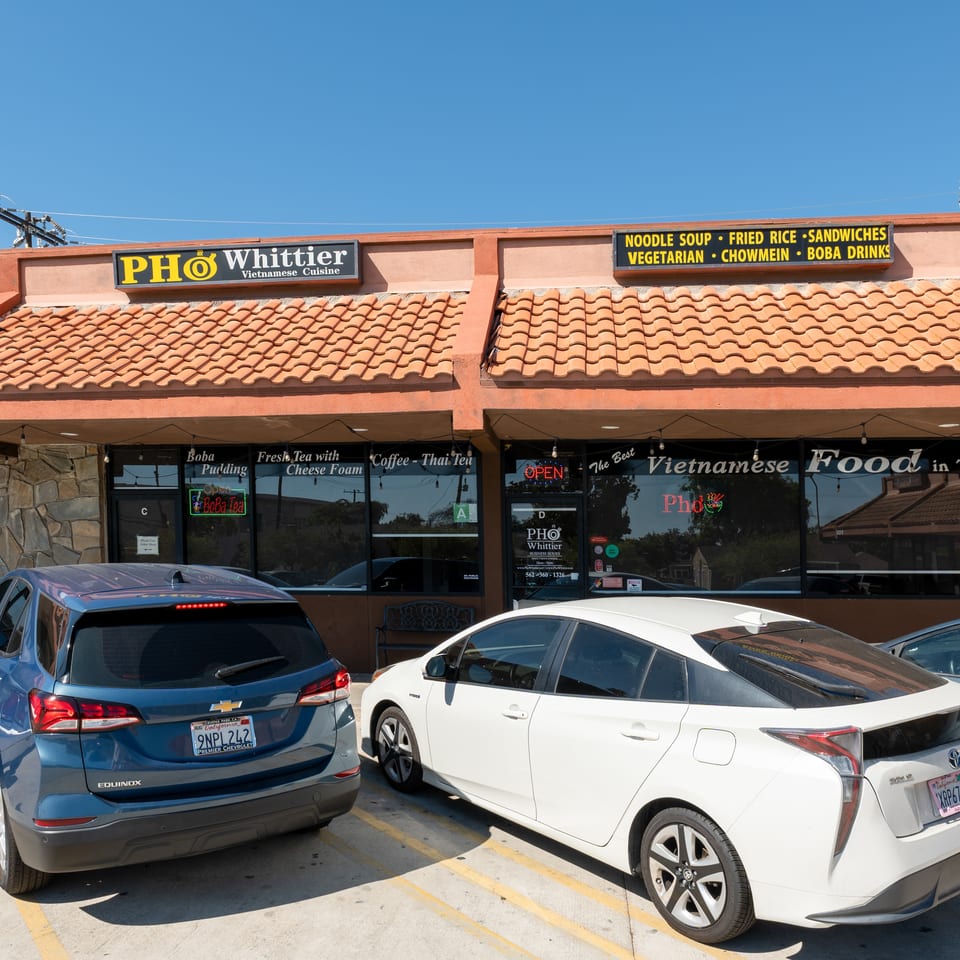 Pho Whittier Vietnamese Cuisine restaurant exterior with cars parked in front on a sunny day.